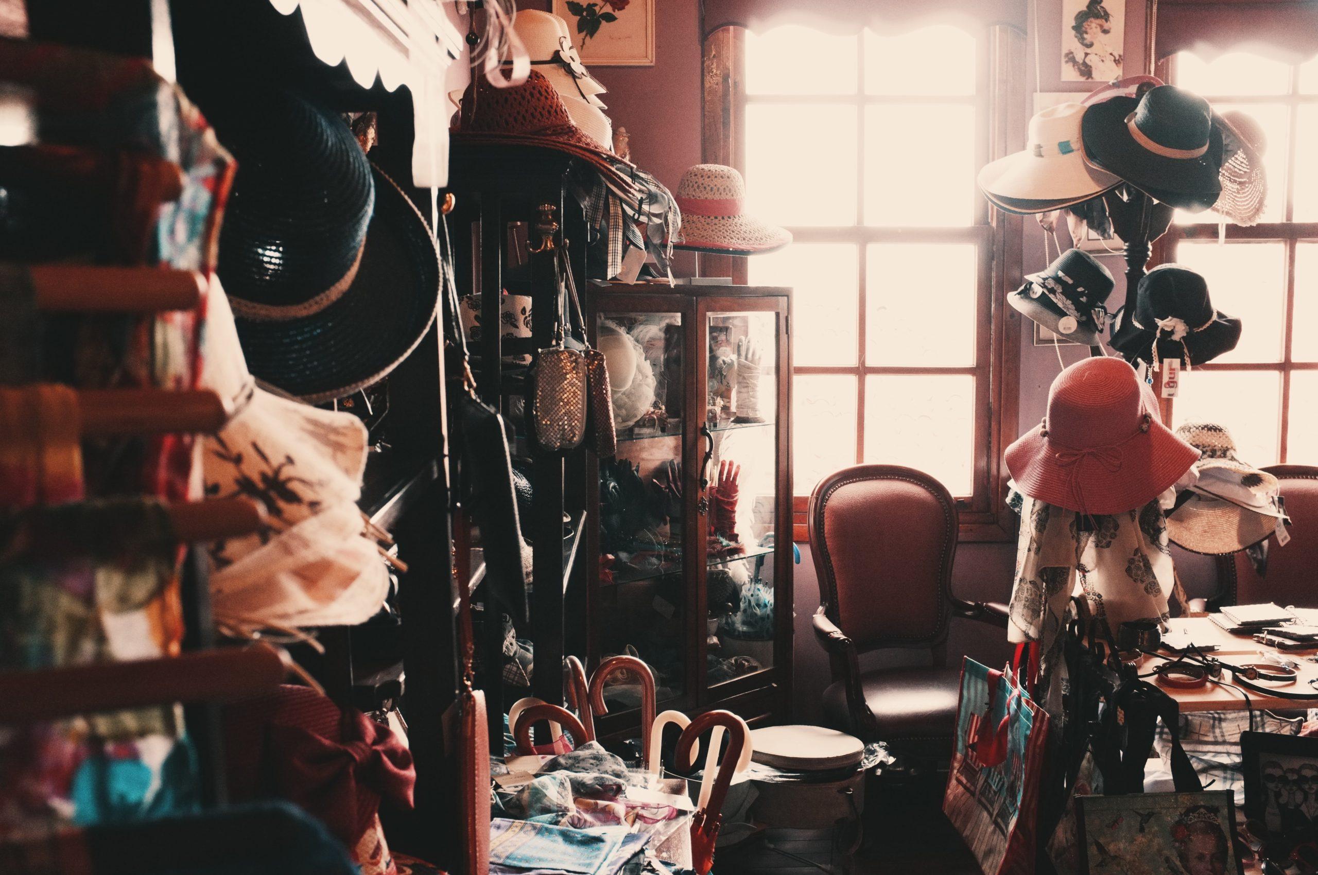 dressing room belonging to someone with a slight hoarding problem with many coat racks and hat racks full of items and all surfaces covered in things